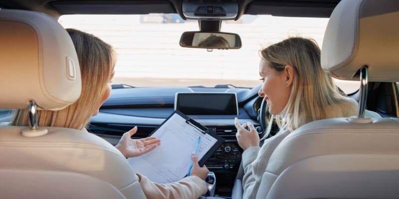 View from back of car showing woman and instructor looking at a clipboard
